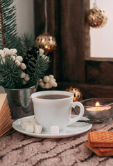 a cup of coffee with white berries, spruce branches, a garland and marshmallows