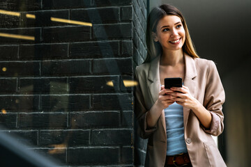 Portrait of successful woman with mobile in urban background. Business technology device concept