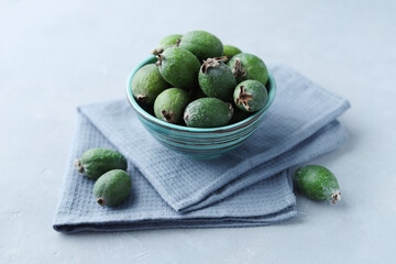Feijoa fruits in the bowl on a gray concrete background. Selective focus.