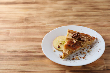 Piece of apple pie on plate on wooden background