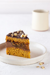 Piece of vegan pumpkin pie with oranges, chocolate and walnuts on a white plate. Sugar, gluten and lactose free.