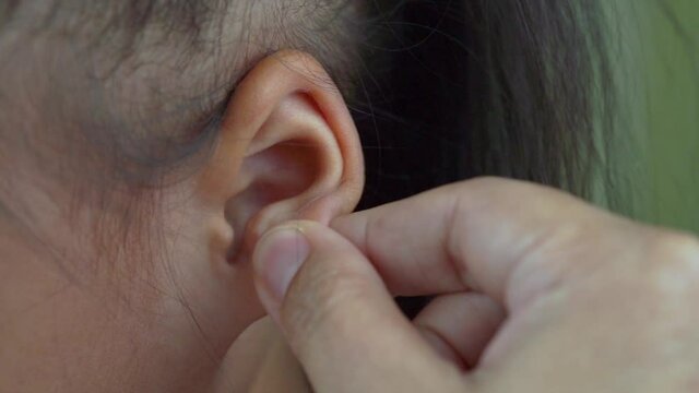 Asian mother and child girl playing pinch ear, touch nose funny face.