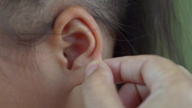 Asian mother and child girl playing pinch ear, touch nose funny face.