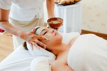 asia woman having face treatment in spa salon on the bed, beauty natural facial mask