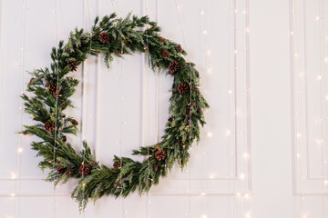 Decorations for the new year, a wreath of fir branches on the wall. Christmas decorative wreath in a cozy home