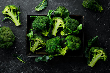 Fresh green broccoli in a wooden box. Top view. On a black background. - obrazy, fototapety, plakaty