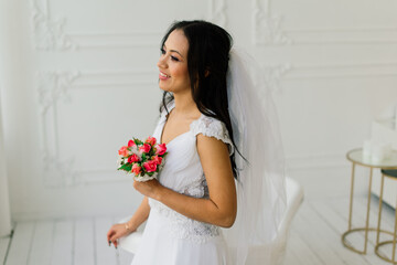 Happy beautiful bride with her veil smiling and excited in interior, wedding morning