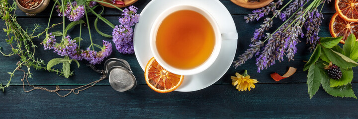 Tea panorama with copy space. Herbs, flowers and fruit around a cup of tea, an overhead flat lay...