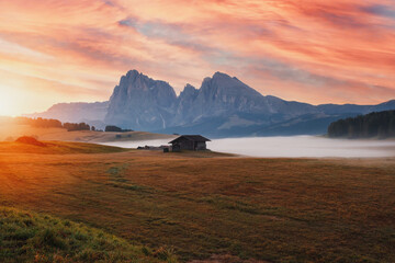 Alpe di Siusi (Seiser Alm) alpine meadow with beautiful sunrise in the background with the Sassolungo and Langkofel mountains visible near the town of Ortisei in the province of South Tyrol