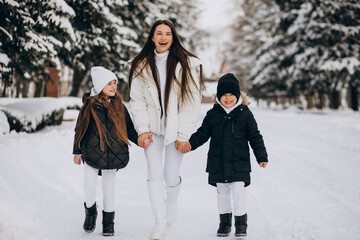 Mother with daughter and son having fun in park full of snow