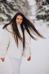 Young woman in white cloths walking in park full of snow
