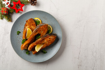 Fried carp in pieces, served on a gray plate. Marbled bright background.