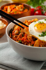 Kimchi cabbage with rice and chicken. Served in a white bowl on a light marble background.