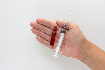 Top view of woman hand holding ampoule with vitamins group B for injection and syringe on the white...