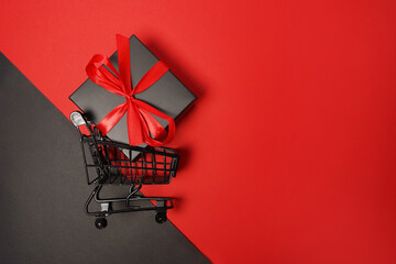 Black Friday sale shopping cart with gift box on red background © Nastya