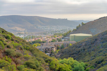 Fototapeta na wymiar View of residential buildings in between green slopes of mountains at Double Peak Park