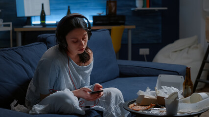 Traumatised, frustrated, stressed, depressed lady listening music at phone looking lost, sitting...