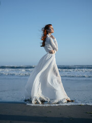 Fototapeta na wymiar Woman in white dress walking along the beach ocean vacation