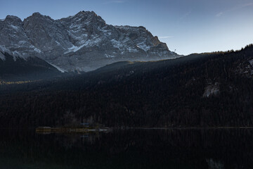 Ein See mit einer kleinen Insel im Vordergrund und hohen Bergen im Hintergrund. Eibsee, Bayern, Deutschland.