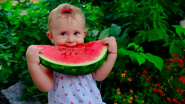 A child eats a watermelon on the street. Selective focus.