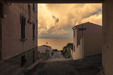 Sonnenuntergang mit tollen leuchtenden Wolken am Himmel in einem kleinen Städtchen am Mittelmeer auf Sardinien, Italien.