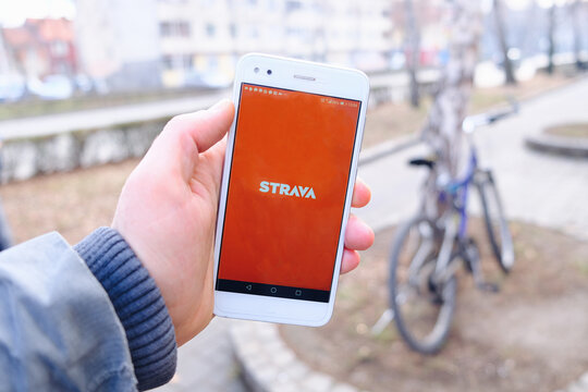 A person holding a mobile phone outdoor closeup, while using sport application Strava