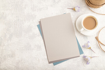 Gray paper sheet mockup with spring snowdrop crocus flowers and cup of coffee on gray concrete background. top view, copy space.