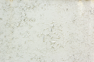 Old Weathered Painted White Plastered Peeled Wall Background. Cracked Flaked Shabby Wall With Rundown Stucco Layer Texture. Cracked peeled white paint with blue spots on an old stone wall.