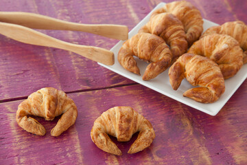 Delicious fresh mini croissants on red wooden background