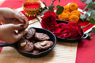 Hands Of Girl Holding Indian Mithai Thekua Thokwa Or Thekuwa Is Made Of Wheat And Meetha Dry Fruits Is Offered to Sun God During Auspicious Chhath Puja Celebrated In Uttar Pradesh Bihar In North India