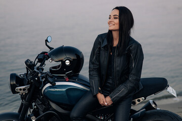 Fototapeta na wymiar Young woman stands next to motorbike near river.