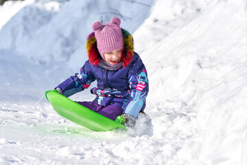 Fototapeta na wymiar Little girl riding on a sled during winter