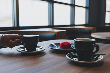 Closeup of a woman drinking hot coffee and eating red velvet lemon tart dessert in cafe