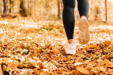 Closeup of running sneaker of the person running in nature with beautiful sunlight during the fall season.
