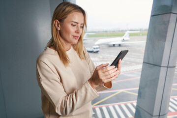 Concentrated tourist using her cellphone in waiting area