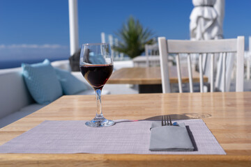 Glass of red wine on a terrace on a sunny day in Santorini Greece