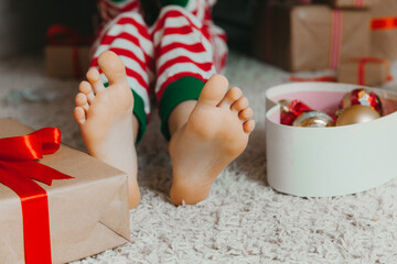bare feet of a child sitting on the floor near the Christmas tree. Close-up.Winter new year...