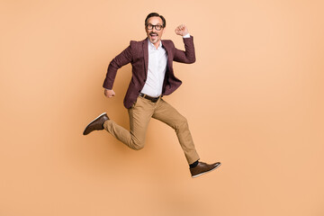 Fototapeta na wymiar Full length body size view of attractive cheerful funky imposing man jumping running movement isolated over beige color background