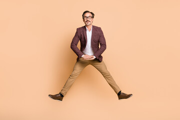 Fototapeta na wymiar Full length body size view of attractive funky man guy executive director jumping having fun isolated over beige color background
