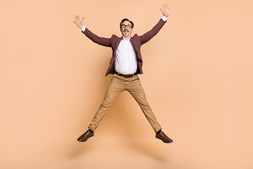 Fototapeta na wymiar Full length body size view of attractive cheerful carefree man guy jumping having fun isolated over beige color background