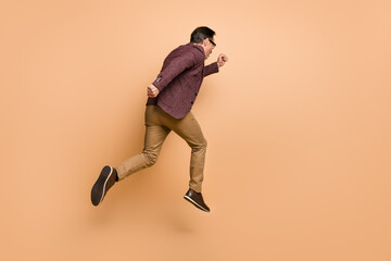 Fototapeta na wymiar Full length body size rear back behind view of attractive motivated man jumping running late hour isolated over beige color background