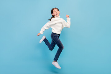 Photo of excited funny student girl wear white sweater smiling jumping high running fast isolated blue color background