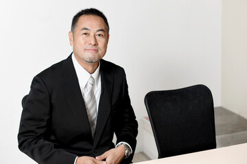 オフィスにいるスーツ姿の笑顔のビジネスマンのミドル男性