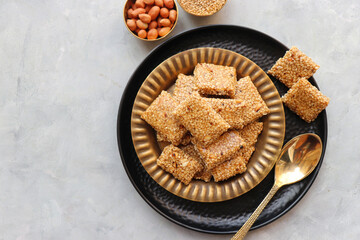 Indian makar sankranti festival food oe sweets. Tilgul in a small brass plate. Tilgul is made out of sesame seeds, peanuts, and jaggery. Til gul ki chikki or sesame candy. Copy Space. Winter food.