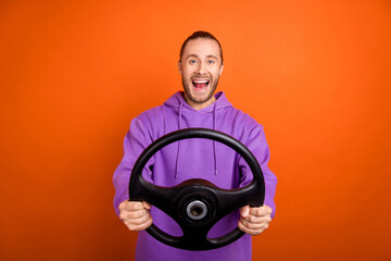 Photo of funny millennial brown tail hairdo guy drive car wear purple sweatshirt isolated on orange...