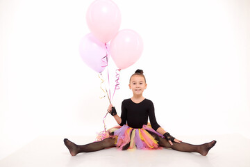 Girl in colorful tutu in the studio with white background during photo shoot with pink balloon....