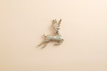Christmas golden reindeer decoration on pastel beige background. Flat lay, top view.