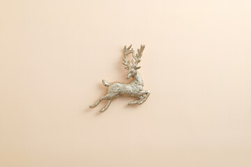 Obraz premium Christmas golden reindeer decoration on pastel beige background. Flat lay, top view.