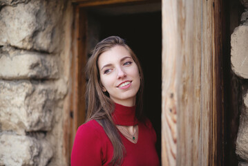 Fototapeta premium Young girl stands near the old door of ancient tower.