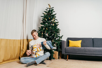 Happy dad tickle son near christmas tree